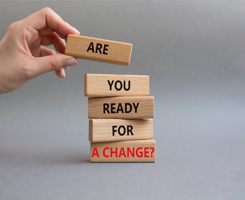 Hand stacking wooden blocks with the words 'Are You Ready For A Change?' to symbolize career transition and personal growth.