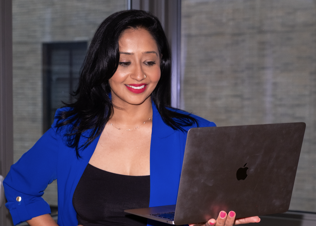 Professional woman in royal blue blazer working on laptop in modern office setting, representing career coaching and job search strategy services