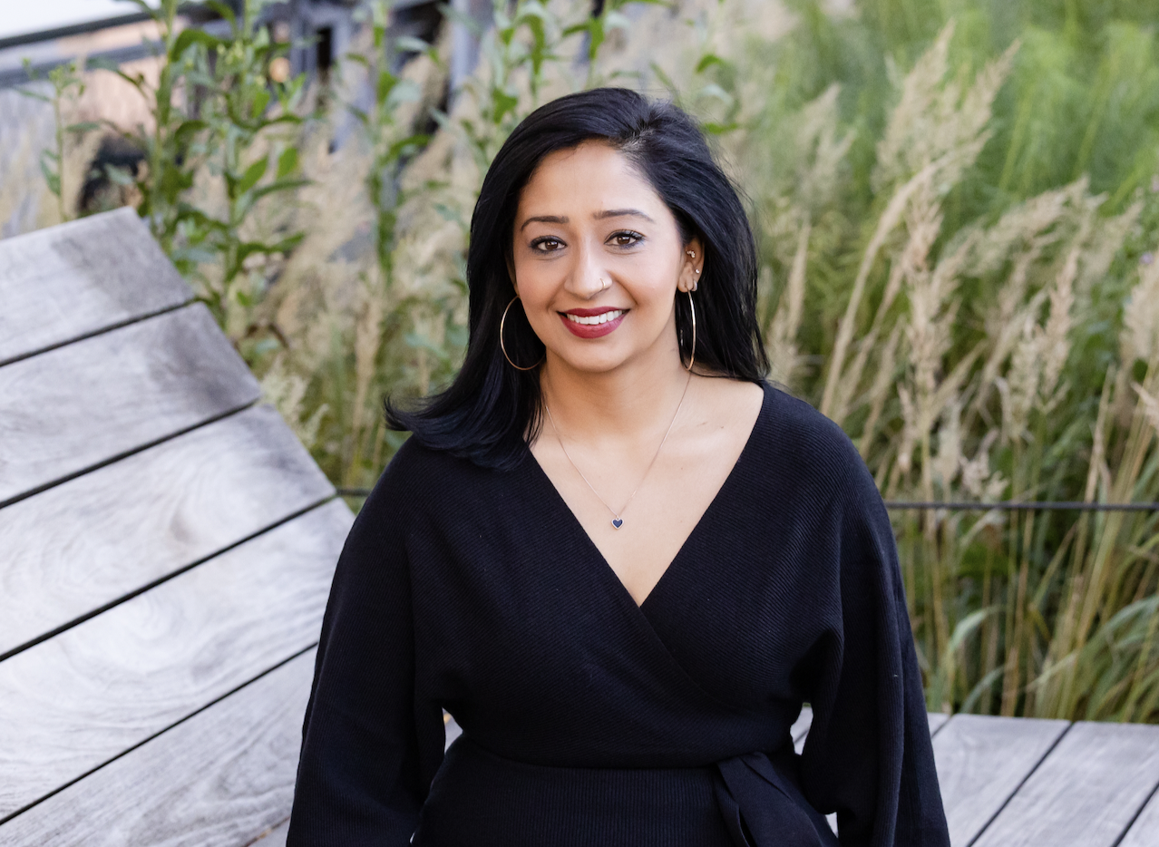 a girl sitting on a bench smiling in a black dress