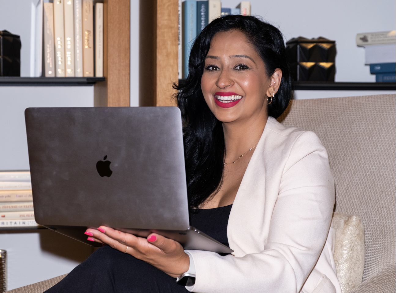 a professional woman sitting crossed legged with her laptop smiling